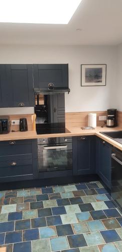Il comprend une cuisine avec des placards bleus et du carrelage. dans l'établissement Gîte 3km Etretat, à Bénouville