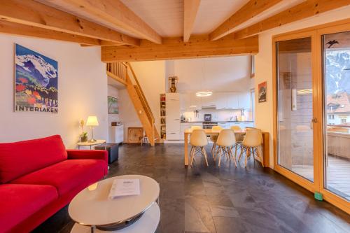 a living room with a red couch and a table at Chalet Apartments Iseltwald in Iseltwald