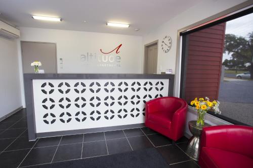 a waiting room with a red chair and a counter at Altitude Motel Apartments in Toowoomba