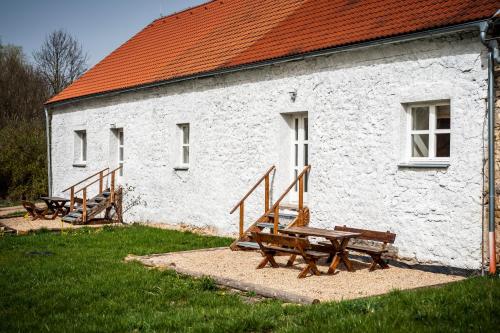 a white building with wooden benches in front of it at Dvůr Dolenec in Rohoznice