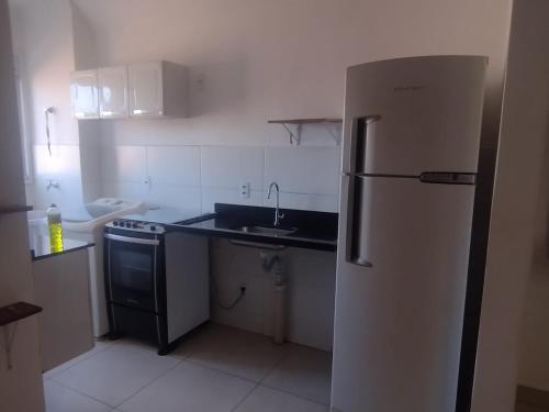 La cuisine est équipée d'un réfrigérateur blanc et d'un évier. dans l'établissement Manacá, à Ribeirão Preto