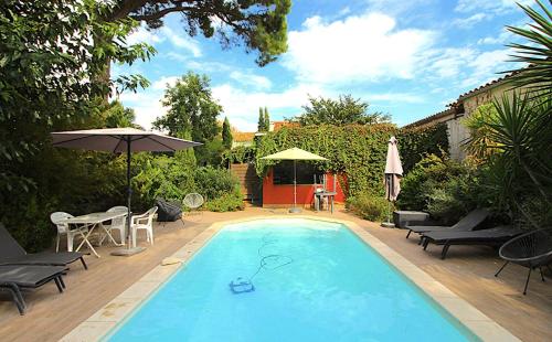 una piscina con mesa, sillas y sombrilla en Chambre BELEM - MAS SAINT LOUIS en Aigues-Mortes