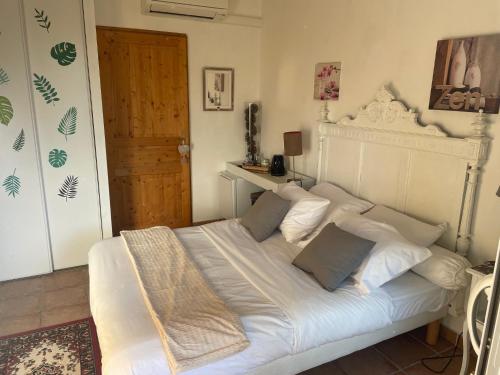 Una cama con sábanas blancas y almohadas en un dormitorio en Chambre BELEM - MAS SAINT LOUIS en Aigues-Mortes