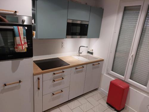 La cuisine est équipée de placards blancs, d'un évier et d'un tabouret rouge. dans l'établissement Appartement vue sur le port, à Martigues