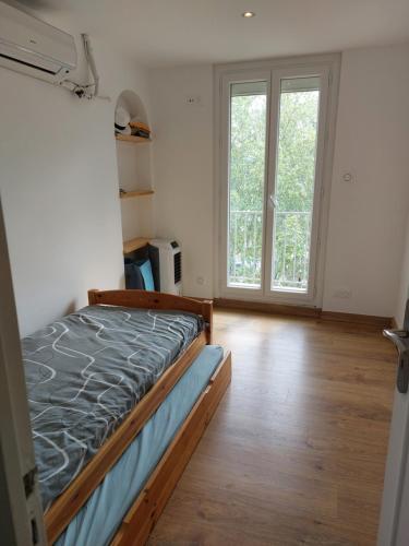 une chambre avec un lit et une grande fenêtre dans l'établissement Appartement vue sur le port, à Martigues