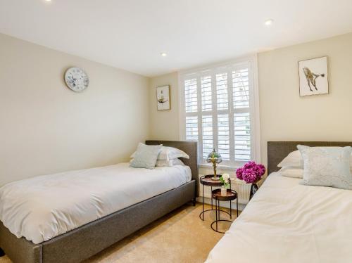 1 dormitorio con 2 camas y ventana en City to Country Retreat Luxury Cottage with Hot Tub, en Toppesfield