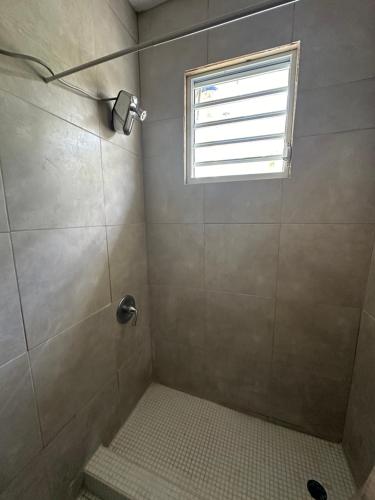 La salle de bains est pourvue d'une douche et d'une fenêtre. dans l'établissement 3BR, 1BA in Cepeda, Up to 20 Guests near Ocean Park Beach, à San Juan