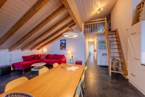 a living room with a red couch and a wooden table at Chalet Apartments Iseltwald in Iseltwald
