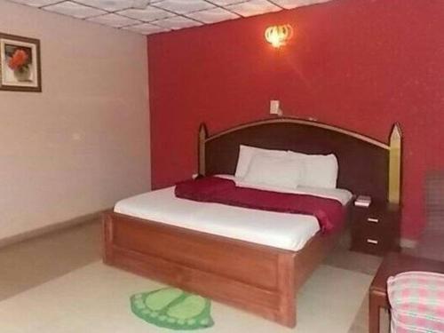 ein Schlafzimmer mit einem Bett mit einer roten Wand in der Unterkunft Precious Palm Royal Hotel in Benin City