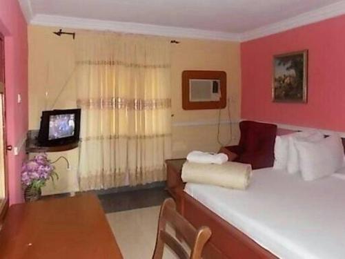 a room with a bed and a table and a television at Precious Palm Royal Hotel in Benin City