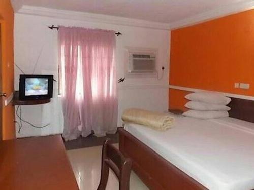 Zimmer mit einem Bett und einem TV. in der Unterkunft Precious Palm Royal Hotel in Benin City