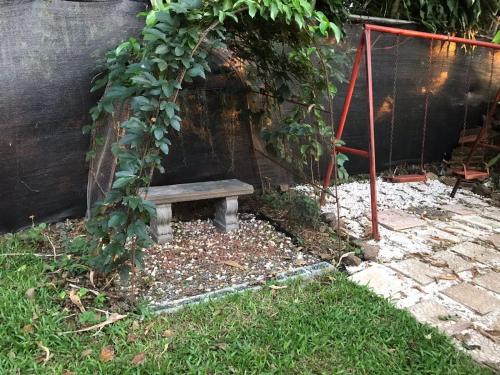 un banco de madera en un jardín con un árbol en Rancho lodge, 