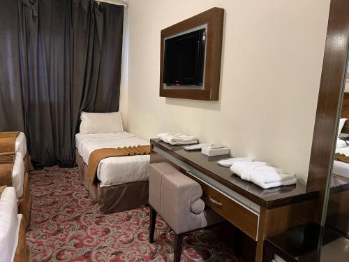 a room with two beds and a desk and a television at Sky View Hotel, Madinah in Medina