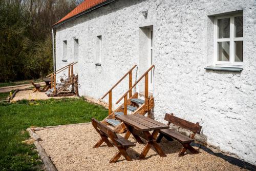 a picnic table and benches in front of a building at Dvůr Dolenec in Rohoznice