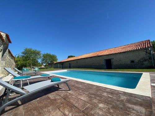 une piscine avec des chaises longues à côté d'un bâtiment dans l'établissement Le Clos de la Bertillère, à Ambleville