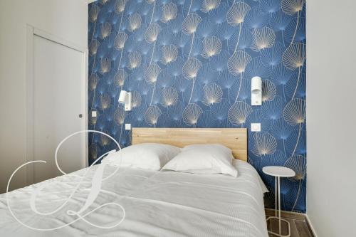 une chambre avec un lit avec un mur bleu dans l'établissement Cyrano, Appartement moderne 2 chambres Paris 14eme, à Paris