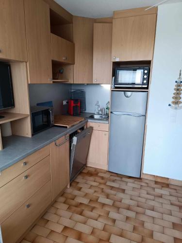 une cuisine avec des armoires en bois et un réfrigérateur blanc dans l'établissement appartement avec terrasse, au Cap d'Agde