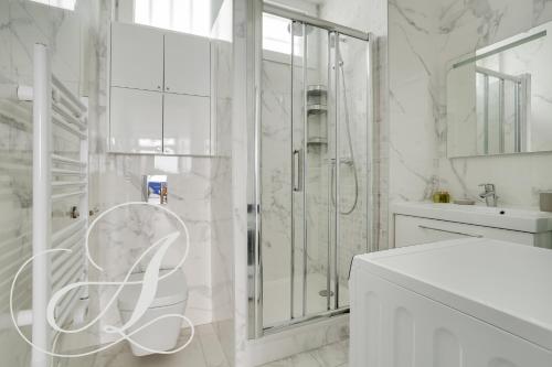 une salle de bain blanche avec une douche et un lavabo dans l'établissement Cyrano, Appartement moderne 2 chambres Paris 14eme, à Paris