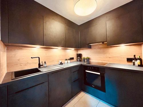 a kitchen with black cabinets and a sink at Sonn-Alm Chalet-Apartments in Bichlbach
