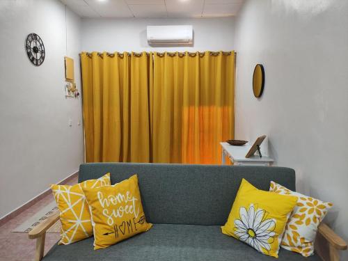 a green couch with yellow pillows in a room at Maileyna Homestay 1.0 in Alor Setar