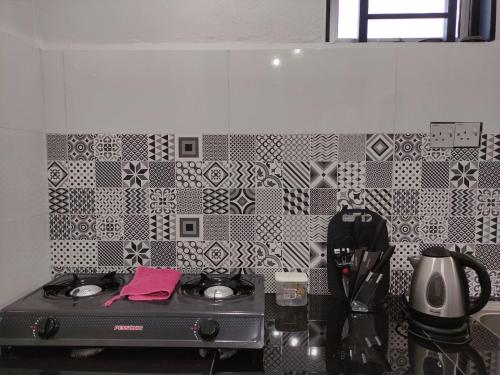 a kitchen with a stove and a tiled wall at Maileyna Homestay 1.0 in Alor Setar