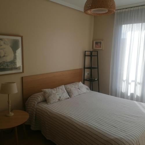 a bedroom with a bed with a striped bedspread and a window at ISLA DE CUBA 2*K. - COLOMBRES in Colombres