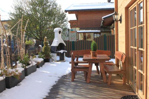 a patio with a table and benches in the snow at Alpen Chalets Zell am See in Niedernsill