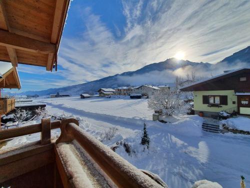 a winter view of a snow covered mountain with the sun setting at Alpen Chalets Zell am See in Niedernsill