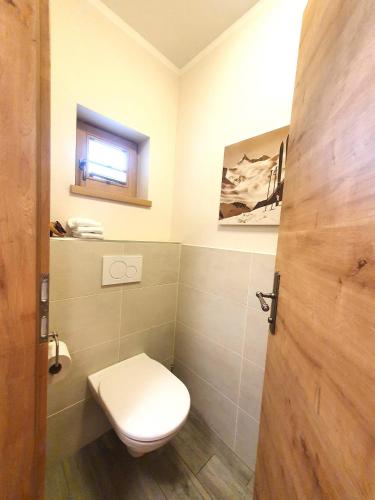 a bathroom with a toilet and a window at Alpen Chalets Zell am See in Niedernsill
