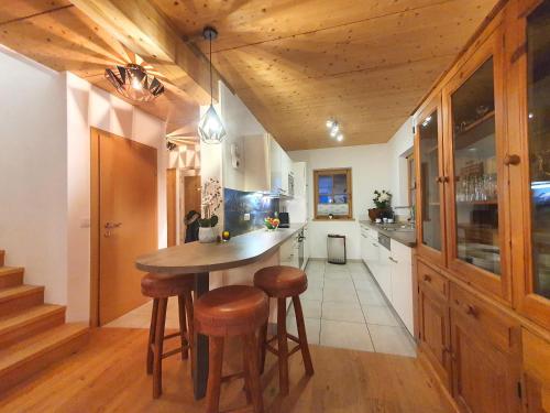 a kitchen with a wooden ceiling and a table and stools at Alpen Chalets Zell am See in Niedernsill
