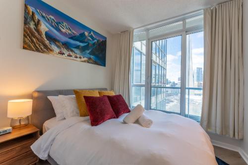 a bedroom with a white bed with a large window at Toronto Views ~ Pool ~ BBQ ~ Harbourfront ~ WIFI in Toronto