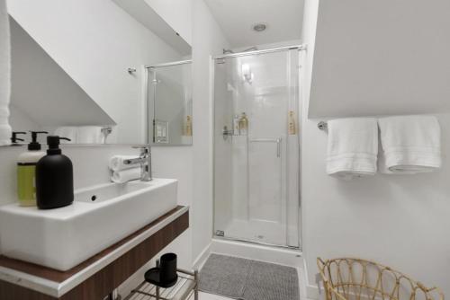 uma casa de banho branca com um chuveiro e um lavatório. em Urban Humble Abode em Seattle