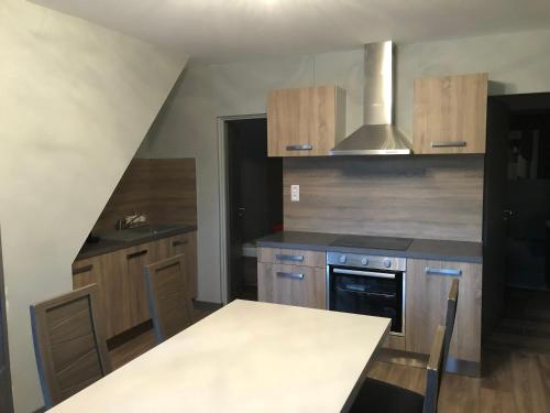 une cuisine avec des armoires en bois et une table à l'intérieur dans l'établissement Le paradis de caux, à Magnac-Bourg