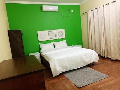 Vila Praia Do BileneにあるKá Jackson Bileneの緑のベッドルーム(ベッド1台、テーブル付)