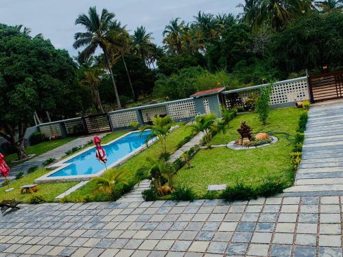 einen Pool in einem Garten mit Palmen in der Unterkunft Ká Jackson Bilene in Vila Praia Do Bilene