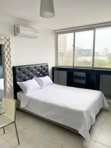 a bedroom with a bed and a chair and a window at Hotel Estefanía Princess 84 in Barranquilla