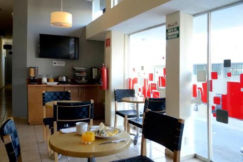 a dining room with tables and chairs and a television at Hotel Mateos 1215 in León