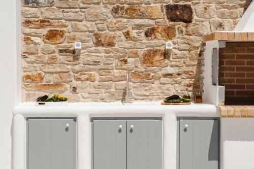 a kitchen with white cabinets and a brick wall at Elaia Retreat Naxos in Vívlos