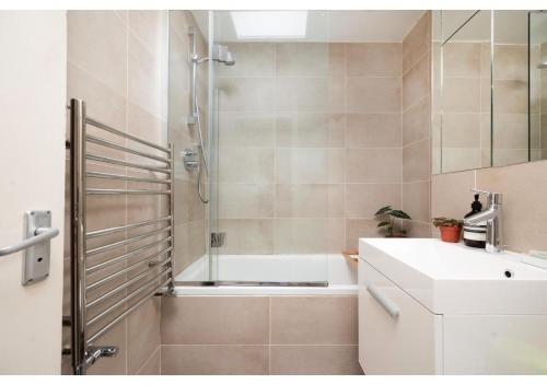 y baño con bañera, lavamanos y ducha. en chic 3-BR home welll located in Islington en Londres