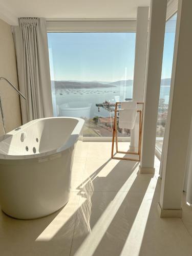a white bath tub in a bathroom with a large window at Otantus Hotel in Muros