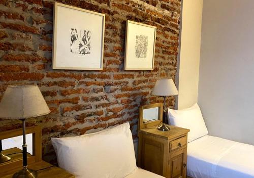 a bedroom with two beds and a brick wall at Posada Gotan in Buenos Aires