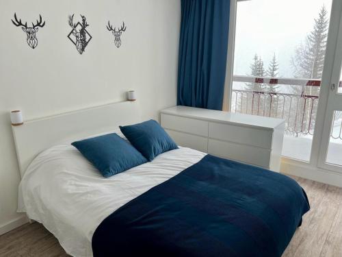 a bedroom with a bed with blue pillows and a window at Appartement Les Arcs 2000, 3 pièces, 7 personnes - FR-1-346-325 in Arc 2000