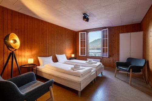 a bedroom with a large bed and two chairs at Chalet Seehus Iseltwald in Iseltwald