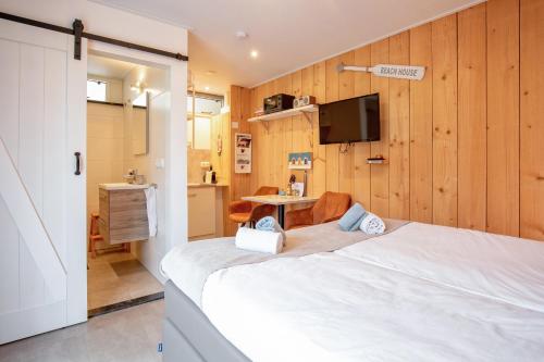 1 dormitorio con 1 cama blanca y TV en Bed en Bike Strûnen op Texel, en Den Burg