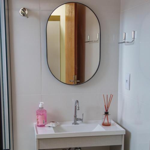 uma casa de banho com um lavatório e um espelho na parede em De Paula Apart Hotel em Espigão dʼOeste