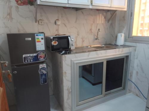 una pequeña cocina con nevera y microondas en Appartement Meublé aux Almadies en Ngor