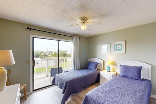 a bedroom with two beds and a balcony at Bay Creek Villa - 202 in Edisto Beach