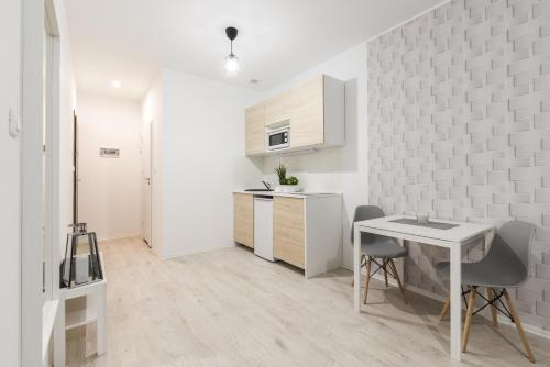 a white kitchen with a table and chairs in a room at Taczaka Apartments Center in Poznań