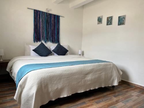 a bedroom with a large bed with blue pillows at Celeste Villa de Leyva in Villa de Leyva