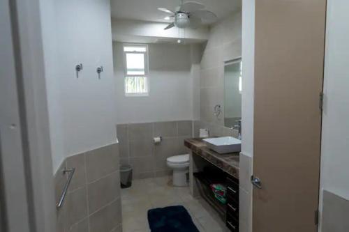 Un baño con inodoro, lavabo y ventana. en La Vida Perezosa, en Caye Caulker